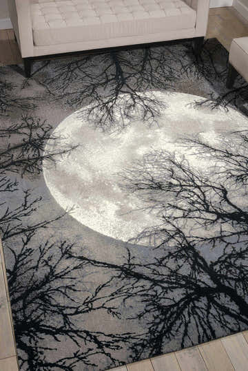 Living room scene with a Nourison Twilight Moon rug featuring a large moon and tree branch design.