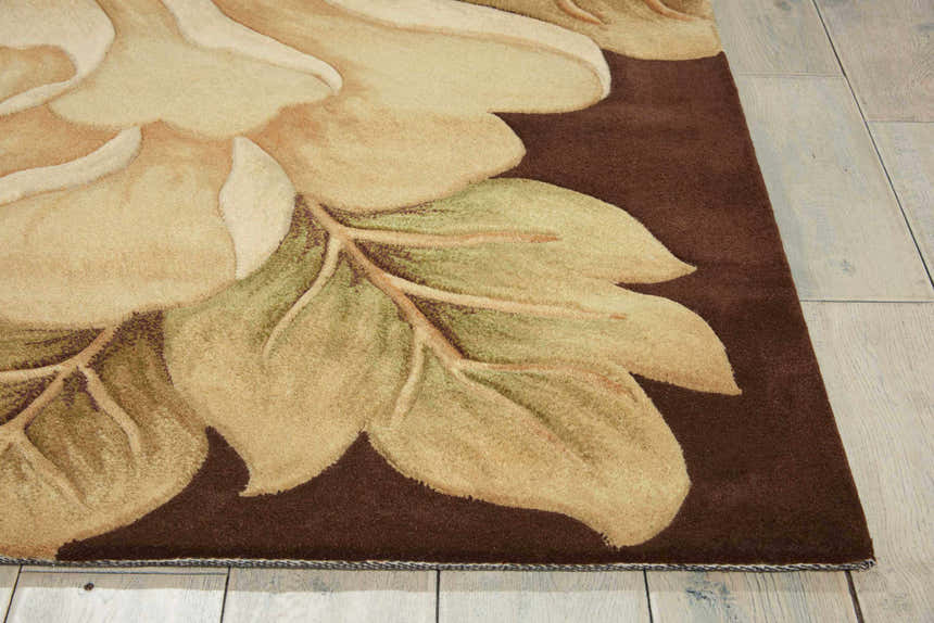 Close-up of the Nourison Tropics Brown area rug. Features a floral design in shades of tan and green on a dark brown background.