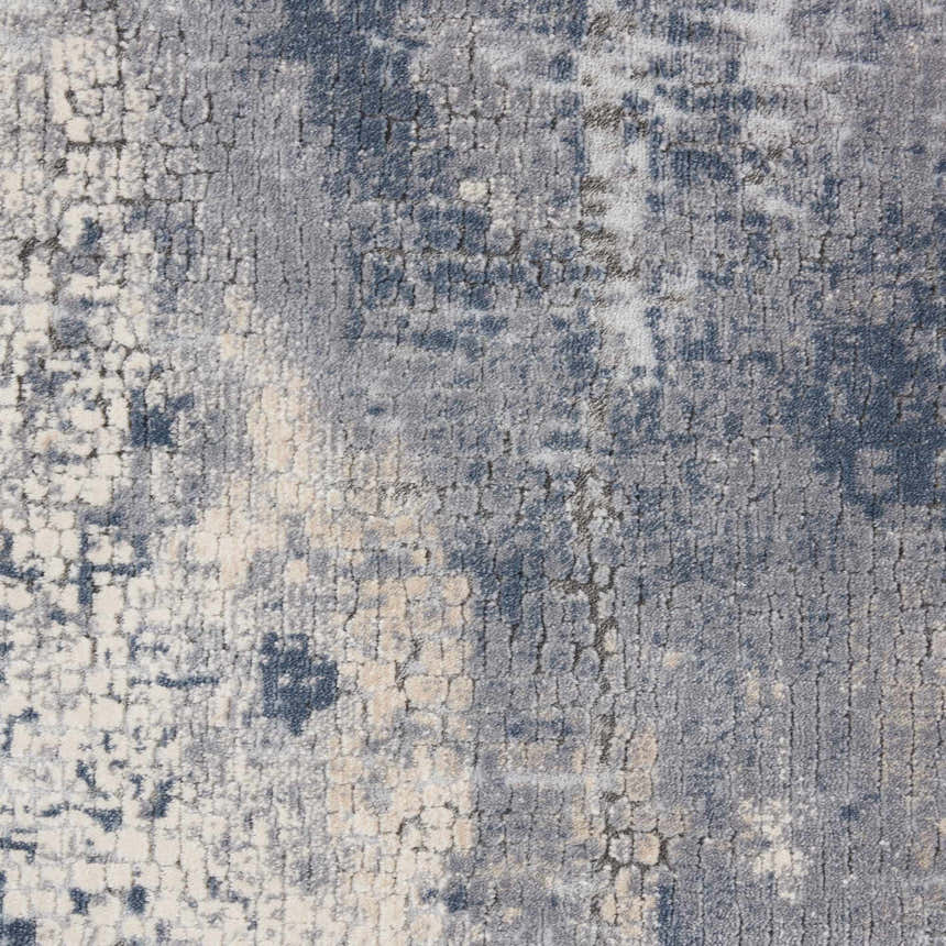 Close-up of the Nourison Rustic Textures Grey Beige rug. Modern design with gray, beige, and blue tones. Abstract pattern.
