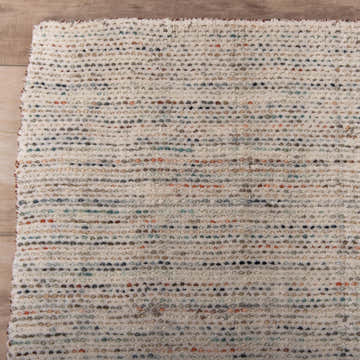 Close up of the hand loomed Rizzy RMI770 area rug. Ivory wool rug with blue, red, green, and orange tones. Corner