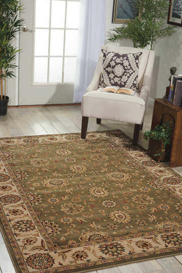 Sunlit room with a Nourison Persian Crown Green rug, cream chair, and wood accents.