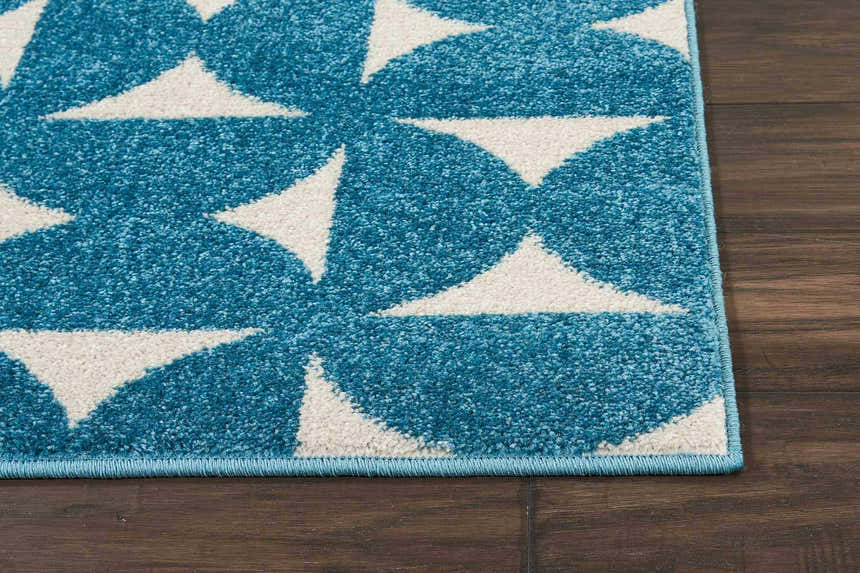 Close-up of Nourison Harper Blue Colorful rug with geometric white pattern on dark wood floor.