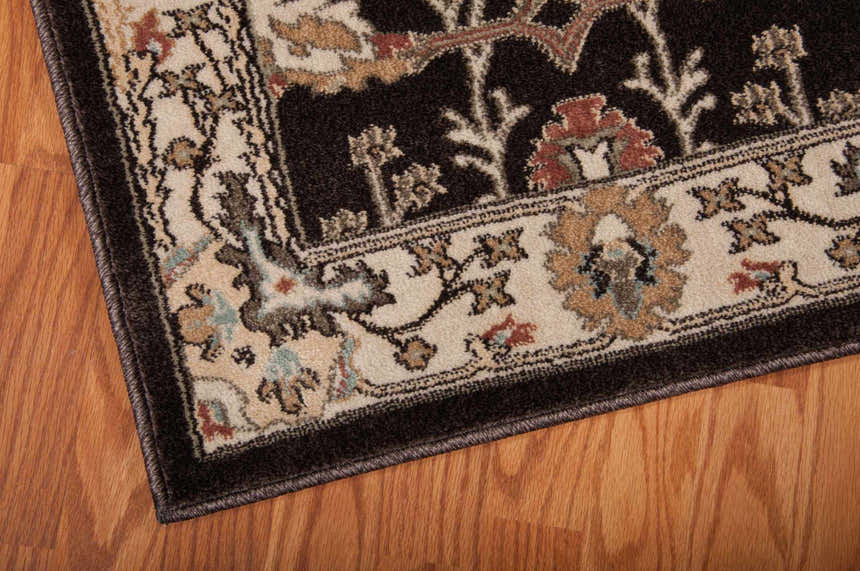 Close up of the Bistre Nourison Walden vintage rug showing floral pattern and brown border on wood floor.