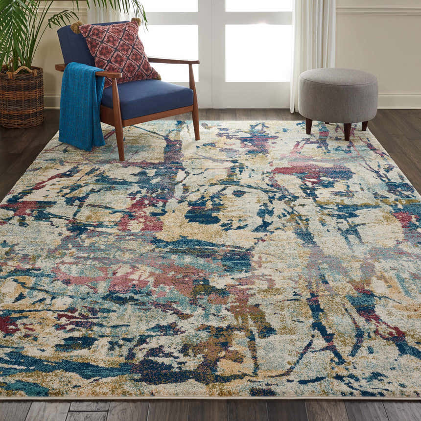 Living room scene with Nourison Fusion Cream Multicolor rug, blue chair, gray ottoman, and indoor plant.