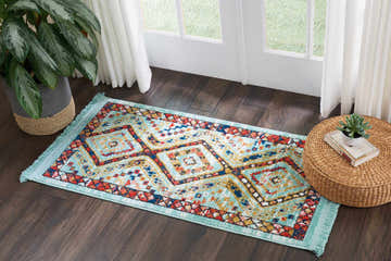 Entryway with Nourison South Western Aqua Tribal rug, dark wood floors, woven ottoman, and potted plant.