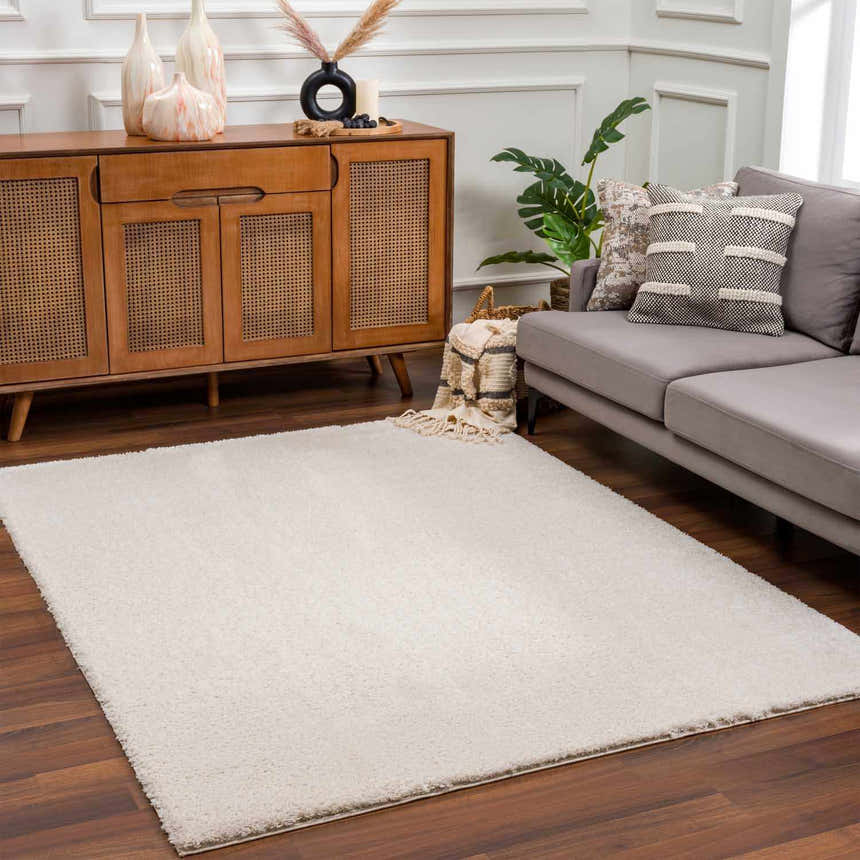 Living room scene with Velora Light Beige Wavy Abstract Rug, wood cabinet, gray sofa, and dark wood floors. Roomscene-Rectangle