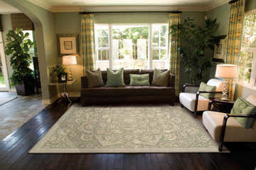 Living room scene with a Nourison Regal Green Persian rug, brown sofa, and white armchairs.