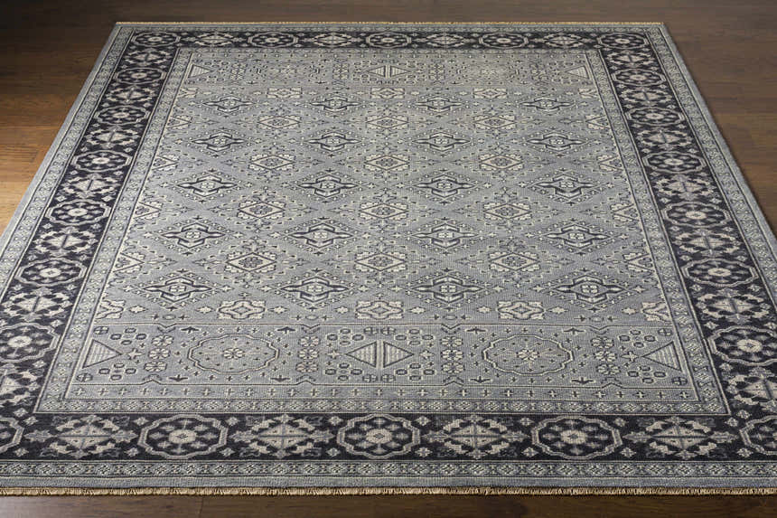 Close-up of the hand-knotted Sherwood Area Rug. Ice blue wool rug with ink blue, teal, and ivory traditional geometric patterns. Front