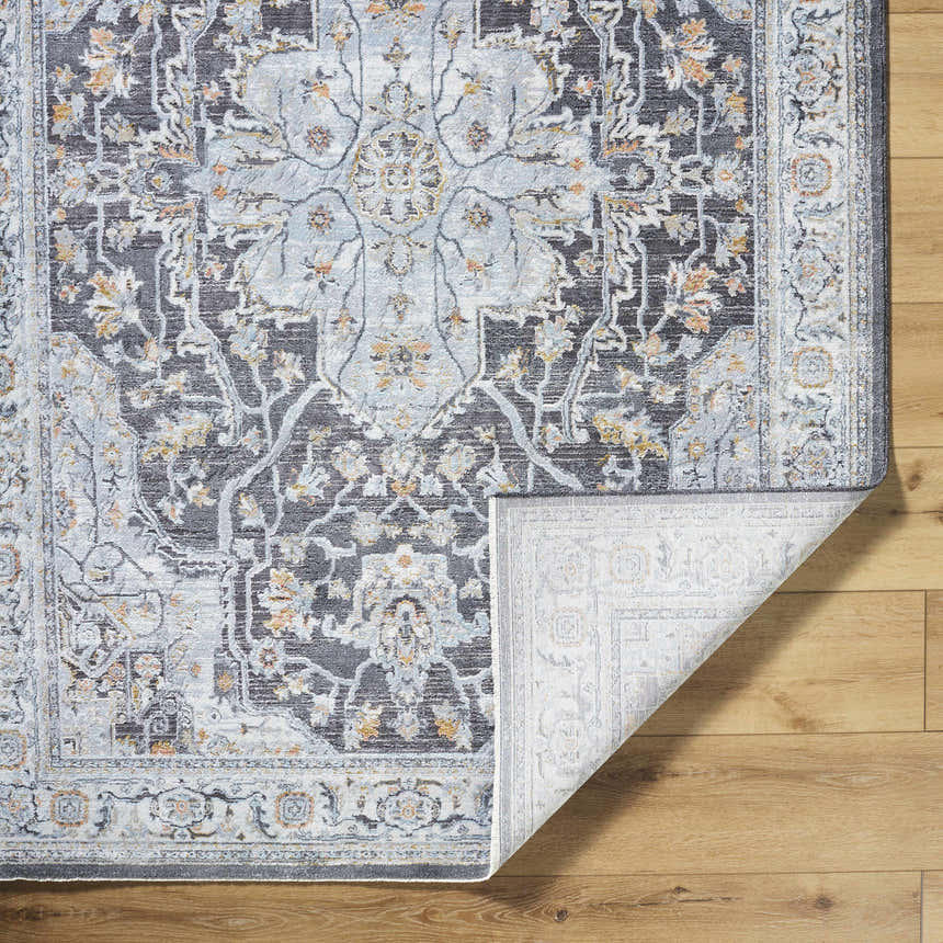 Close-up of the Hayfa Area Rug. Dark gray, light gray, and blue traditional floral pattern. Machine woven texture. Fold