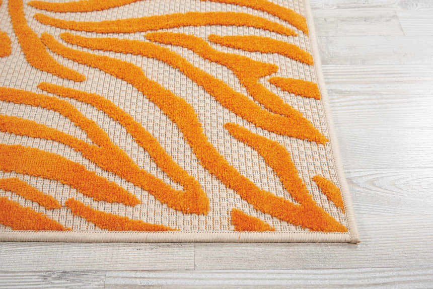 Close-up of the Nourison Aloha Orange rug, showing a contemporary burnt orange tiger-stripe design and woven texture.