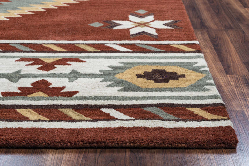 Close-up of the hand-tufted Rizzy SU1822 area rug. Southwestern style with navy, off-white, red, sage, and tan colors. Corner