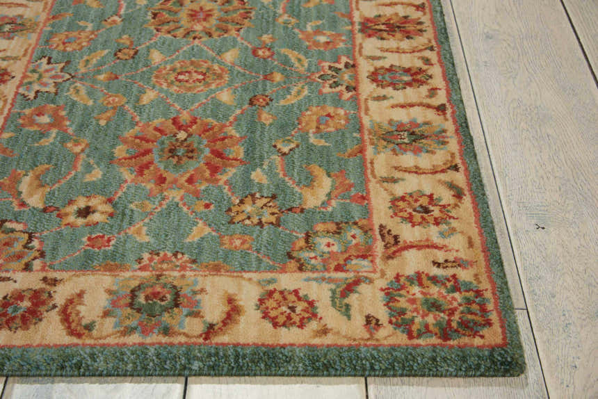 Close-up of the aqua Nourison Living Treasures rug, featuring a traditional floral pattern and a beige border on a wood floor.