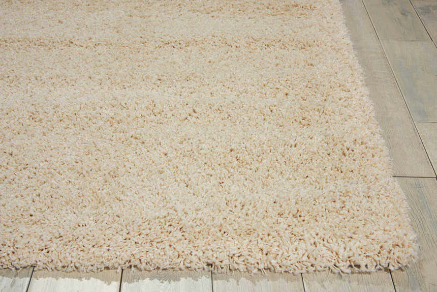 Close-up of the plush texture of the Nourison Amore Cream Shag Rug on light wood flooring.