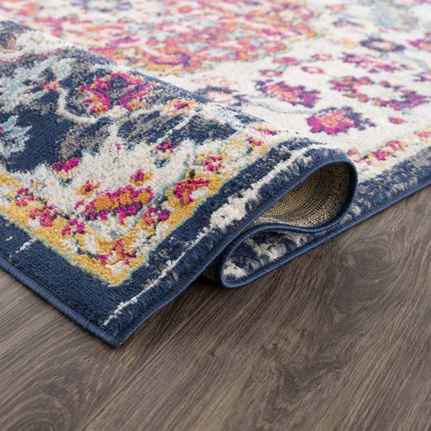 Close up of Tigril Blue & Orange 2304 Area Rug showing floral pattern, navy border, and ivory, pink, and yellow accents. Fold