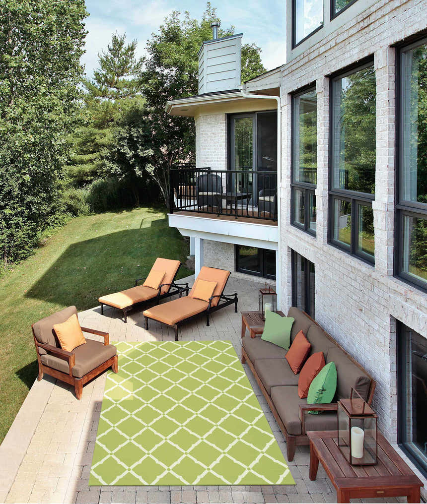 Outdoor patio scene with a Nourison Home & Garden Light Green area rug, brown furniture, and lounge chairs.
