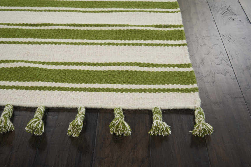 Close-up of the ivory and green striped Nourison Rio Vista rug with fringe tassels on a dark wood floor.