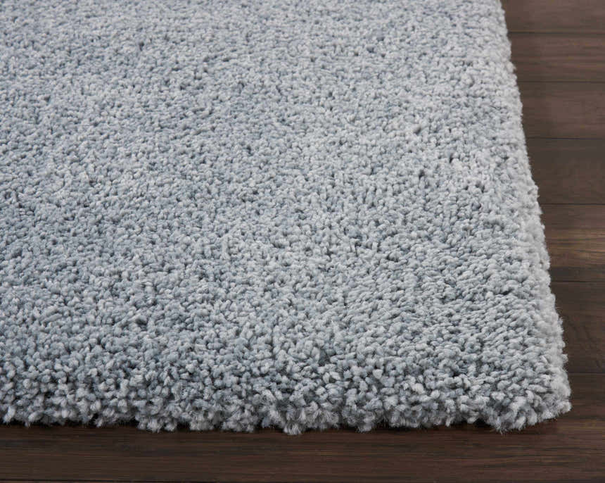 Close-up of the plush texture of the Nourison Malibu Shag Slate rug on a dark wood floor.