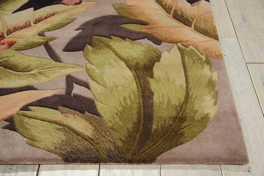 Close-up of the handmade Nourison Tropics Plum rug. Features a dark purple background and large, green and brown leaf design.