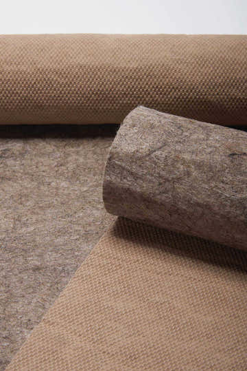 Close-up of a rolled Nourison Loc Non-slip Pad Area Rug showing its texture and gray color.