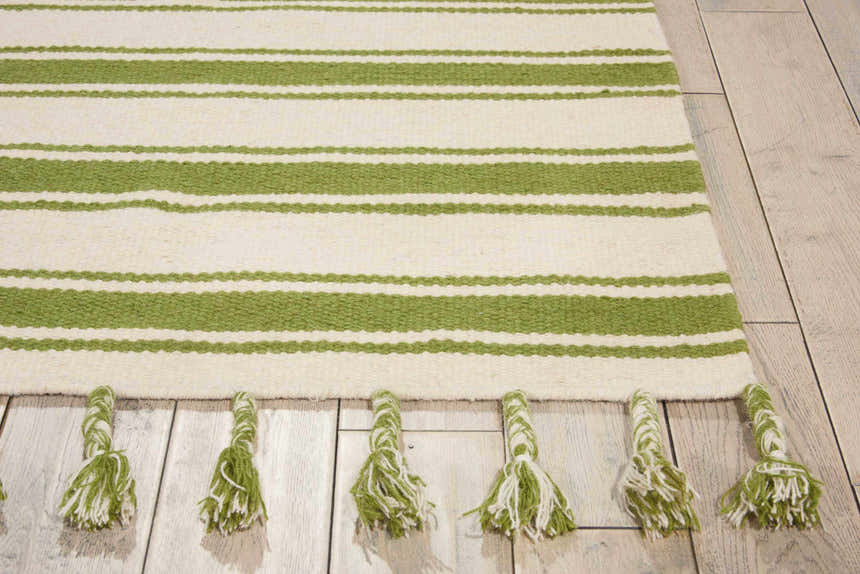 Close-up of Nourison Rio Vista Ivory/Green rug. Wool rug with green stripes and knotted fringe on light wood floor.