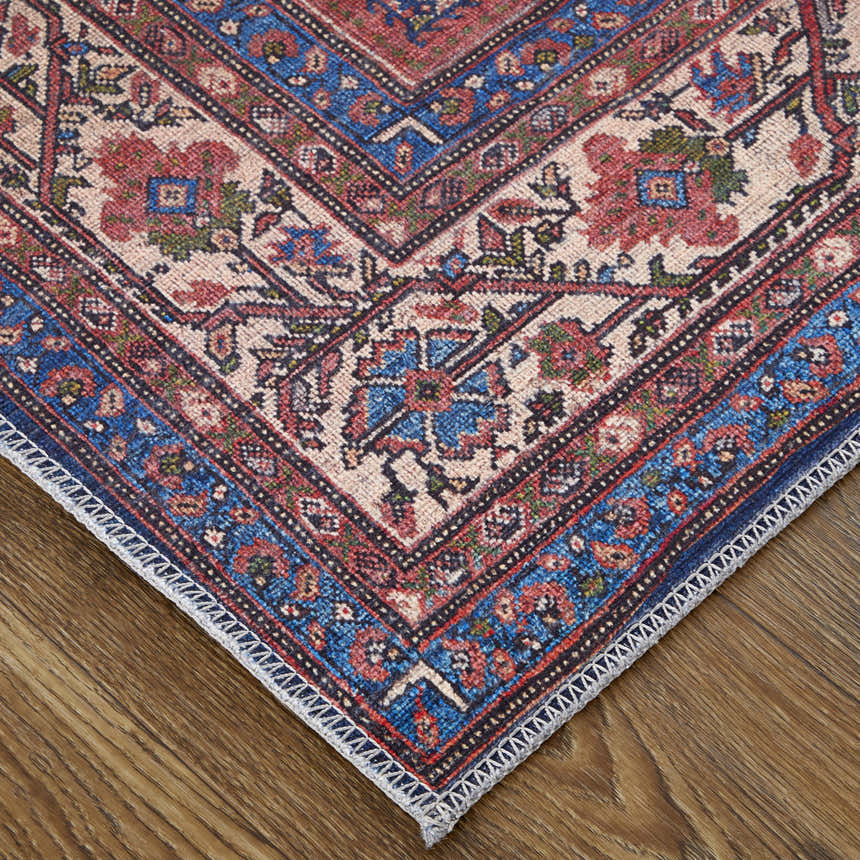 Close-up of Feizy Rawlins rug showing red, blue, and tan oriental pattern. Transitional style rug on wood floor. Corner