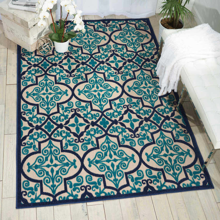 Living room scene with a Nourison Aloha Navy Bohemian Area Rug, white bench, and wood floors.