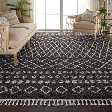 Living room scene with a Nourison Moroccan Shag Charcoal Tribal rug, beige sofa and chair, and dark wood floors.