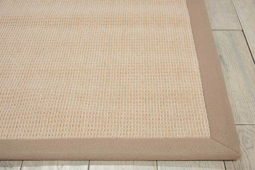 Close-up of the Nourison Sisal Soft Eggshell rug, showing its beige woven texture and contrasting tan border.