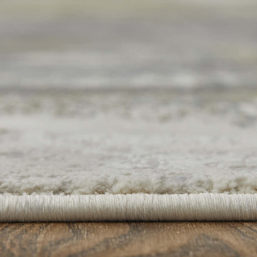 Close-up of the Feizy Clio rug showing its texture, edge binding, and brown, gray, and black watercolor design. Pile