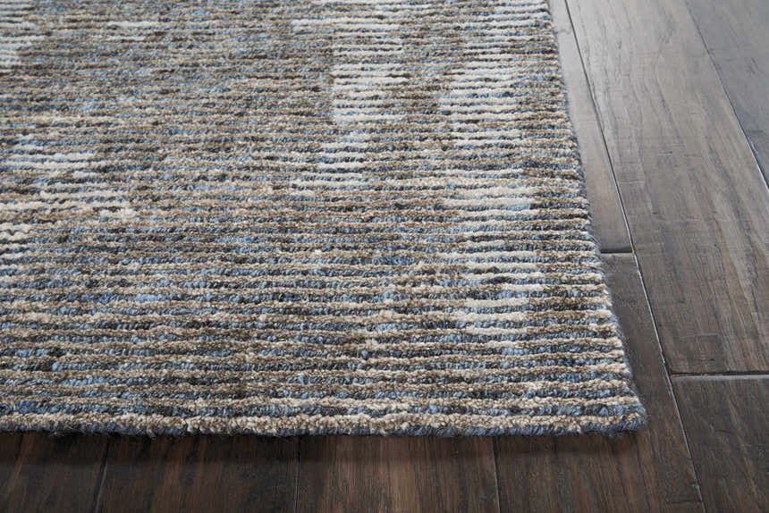 Close up of the textured Nourison Ellora Slate rug in taupe and blue on a dark wood floor.