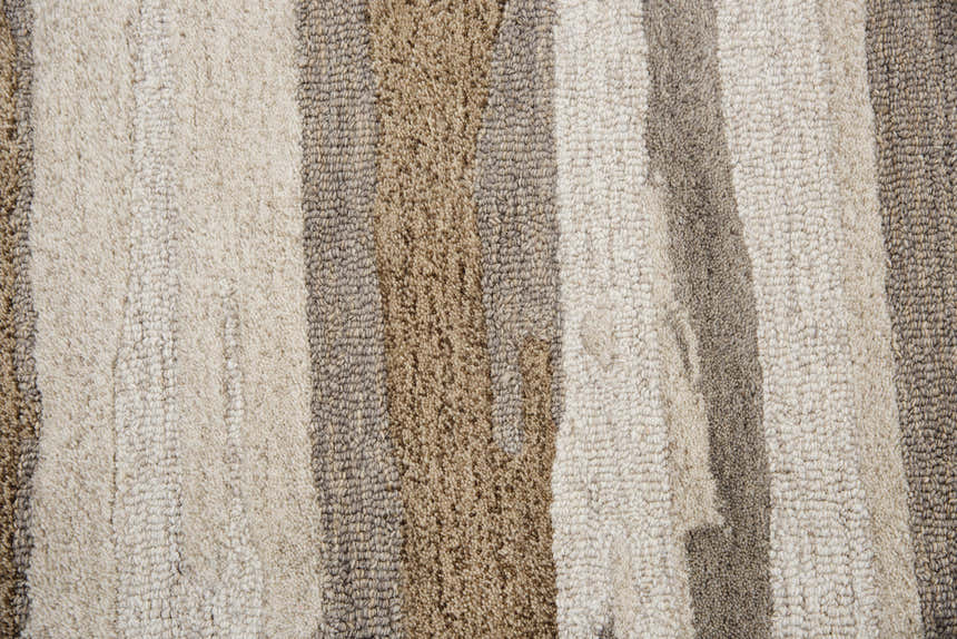 Close-up of the hand-tufted Rizzy VOG101 rug. Beige, brown, and gray stripes create a contemporary pattern. 100% wool texture. Texture