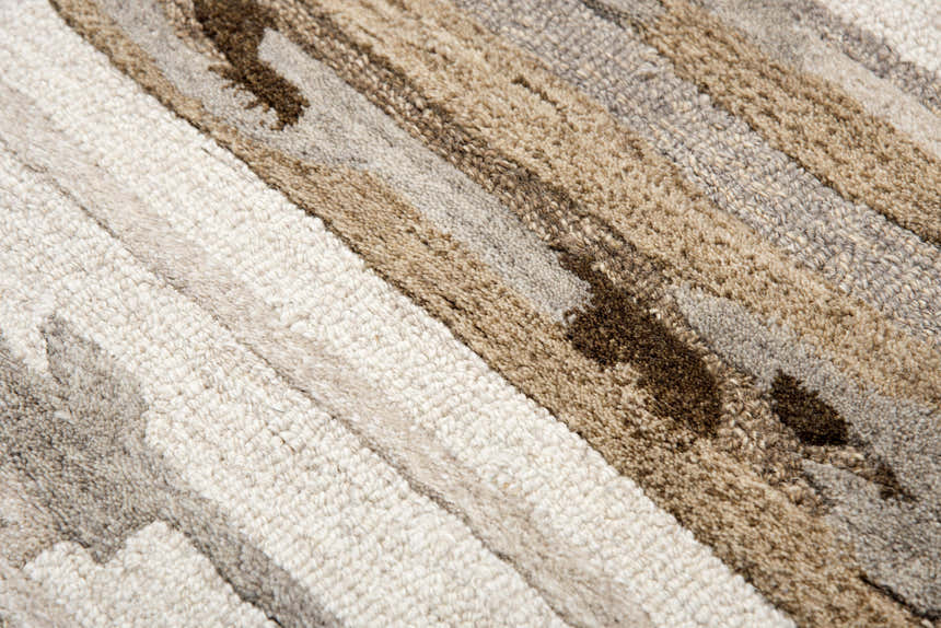 Close-up of the hand-tufted Rizzy VOG101 area rug. Beige, dark red, and brown wool create a contemporary striped pattern. Texture