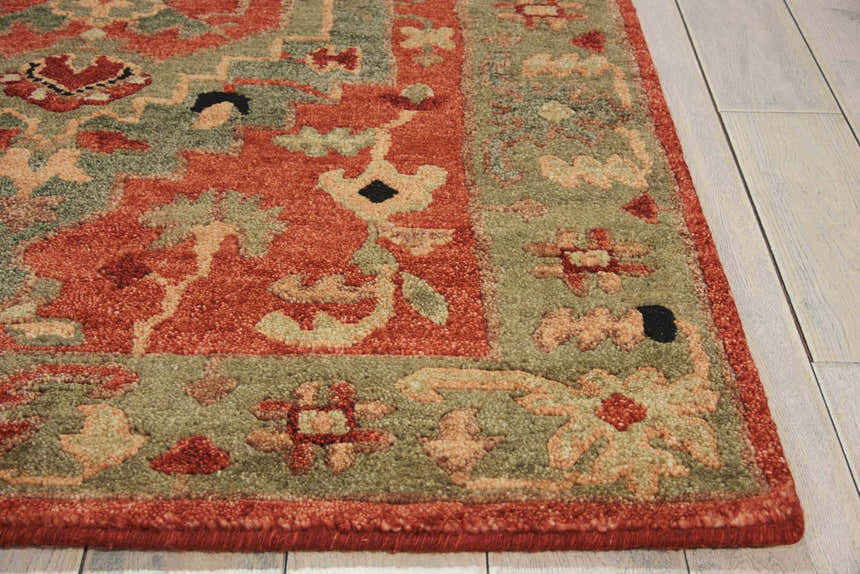 Close-up of the handmade Nourison Tahoe Rust rug. Traditional floral pattern in rust, green, and beige wool. Farmhouse style.