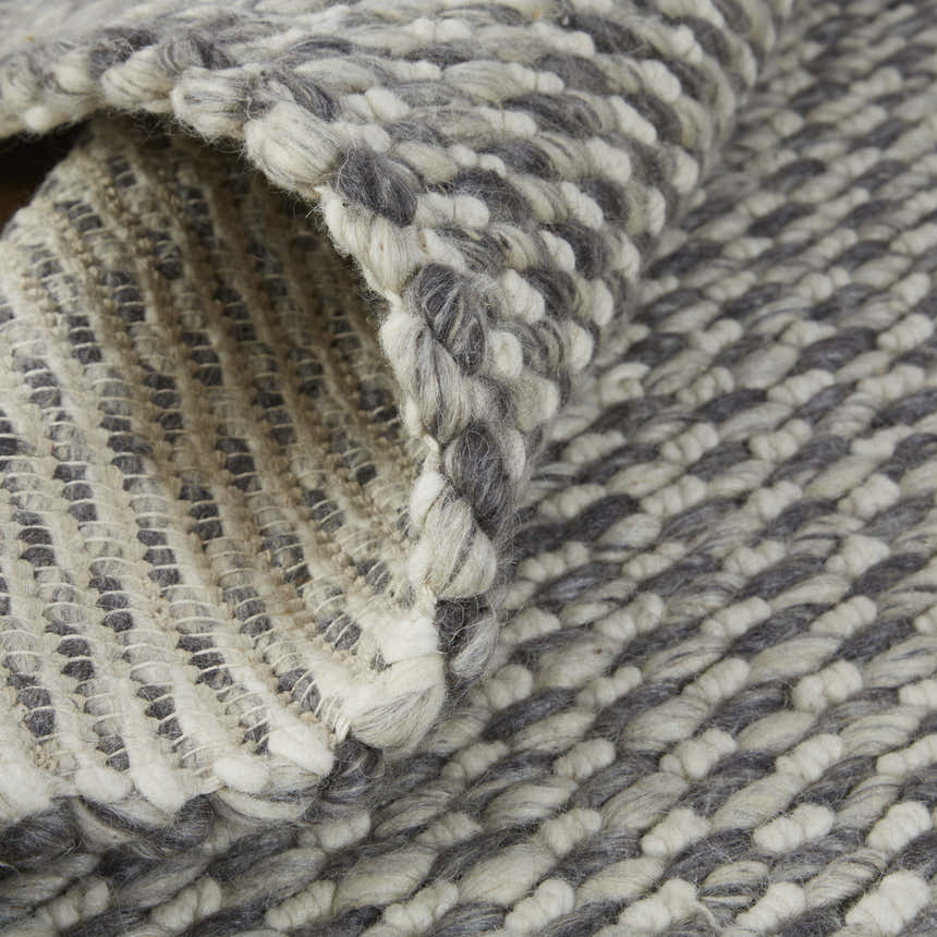 Close-up of the Feizy Berkeley Gray/Ivory rug showing hand woven texture and wool material. Fold