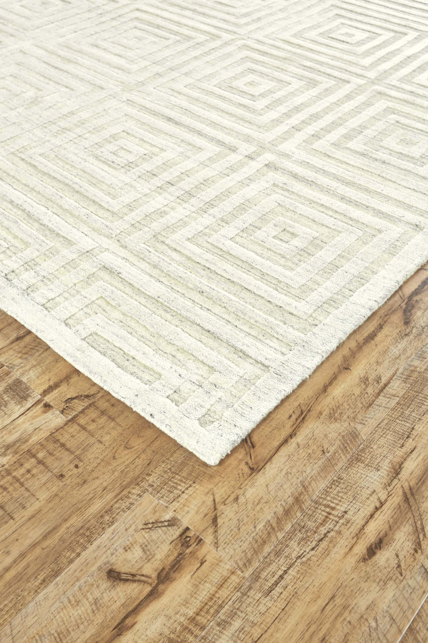 Close-up of the Feizy Gramercy Ivory Area Rug showing a geometric pattern and hand woven texture on a wood floor. Corner