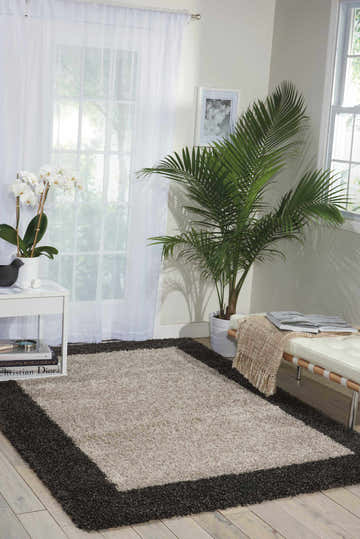 Bright living room with a Nourison Amore Silver Charcoal Shag Rug, plants, and white furniture.