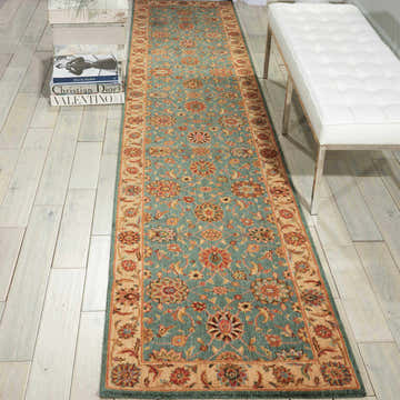 Entryway scene with aqua Nourison Living Treasures rug runner, white bench, and fashion books on light wood floors.