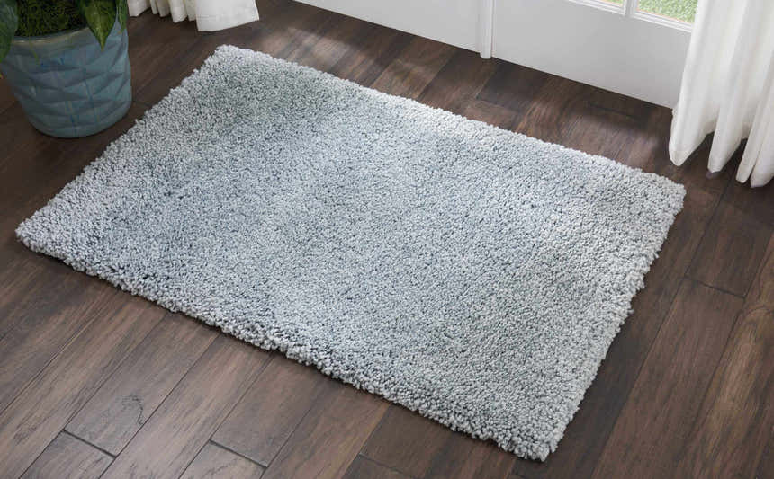 Close-up of a slate Nourison Malibu Shag rug on dark wood floors, showing its plush texture.