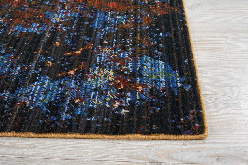 Close up of Nourison Chroma Red Flare rug showing abstract red, blue, and gold pattern on a dark background.