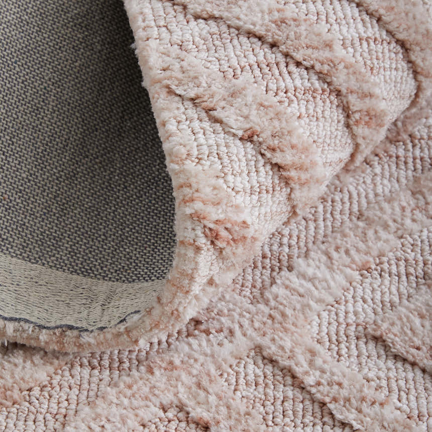 Close-up of the Feizy Colton Modern Diamond rug in pink and ivory, showing its plush texture and geometric design. Fold