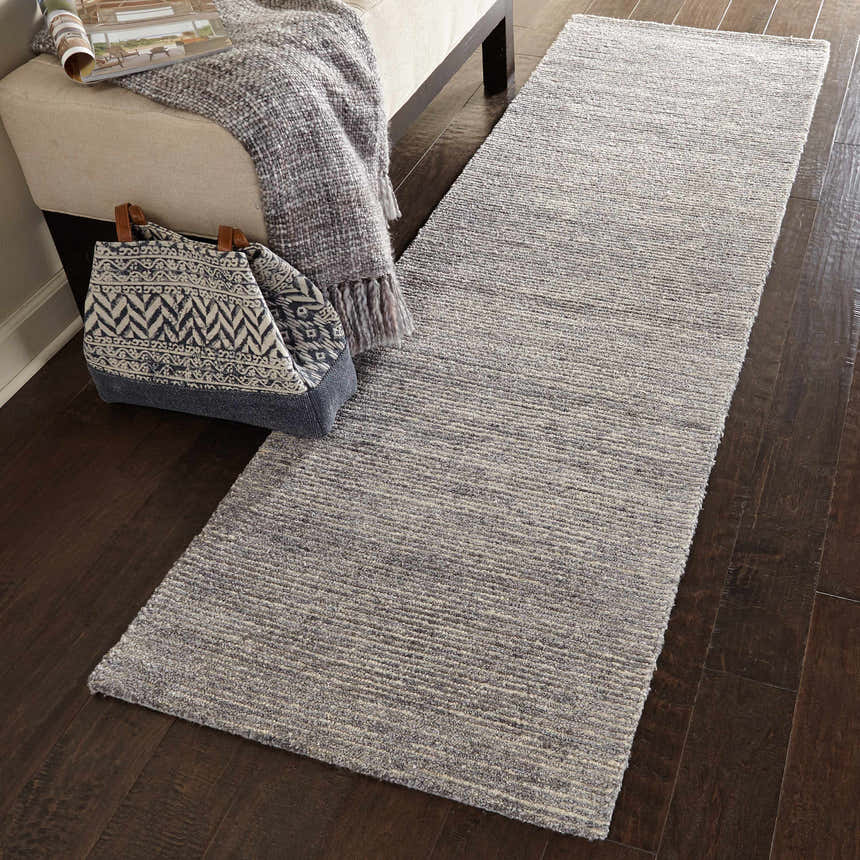 Hallway scene with a Nourison Weston Silver Birch runner rug on dark wood floors, styled with a bench and patterned tote.