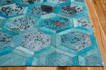 Close-up of the Michael Amini City Chic Turquoise rug. Aqua leather hexagons with a speckled pattern on a wood floor.