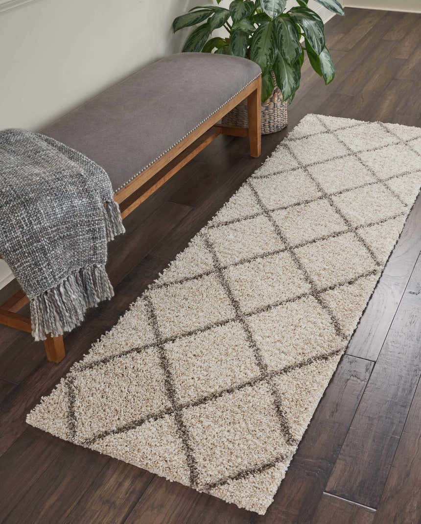 Hallway scene with a Nourison Brisbane Cream Shag rug runner, gray bench, throw blanket, dark wood floors, and potted plant.