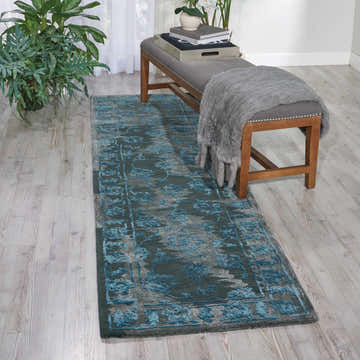 Entryway scene with Nourison Opaline Charcoal Blue vintage runner rug, gray bench, wood floors, and potted plant.