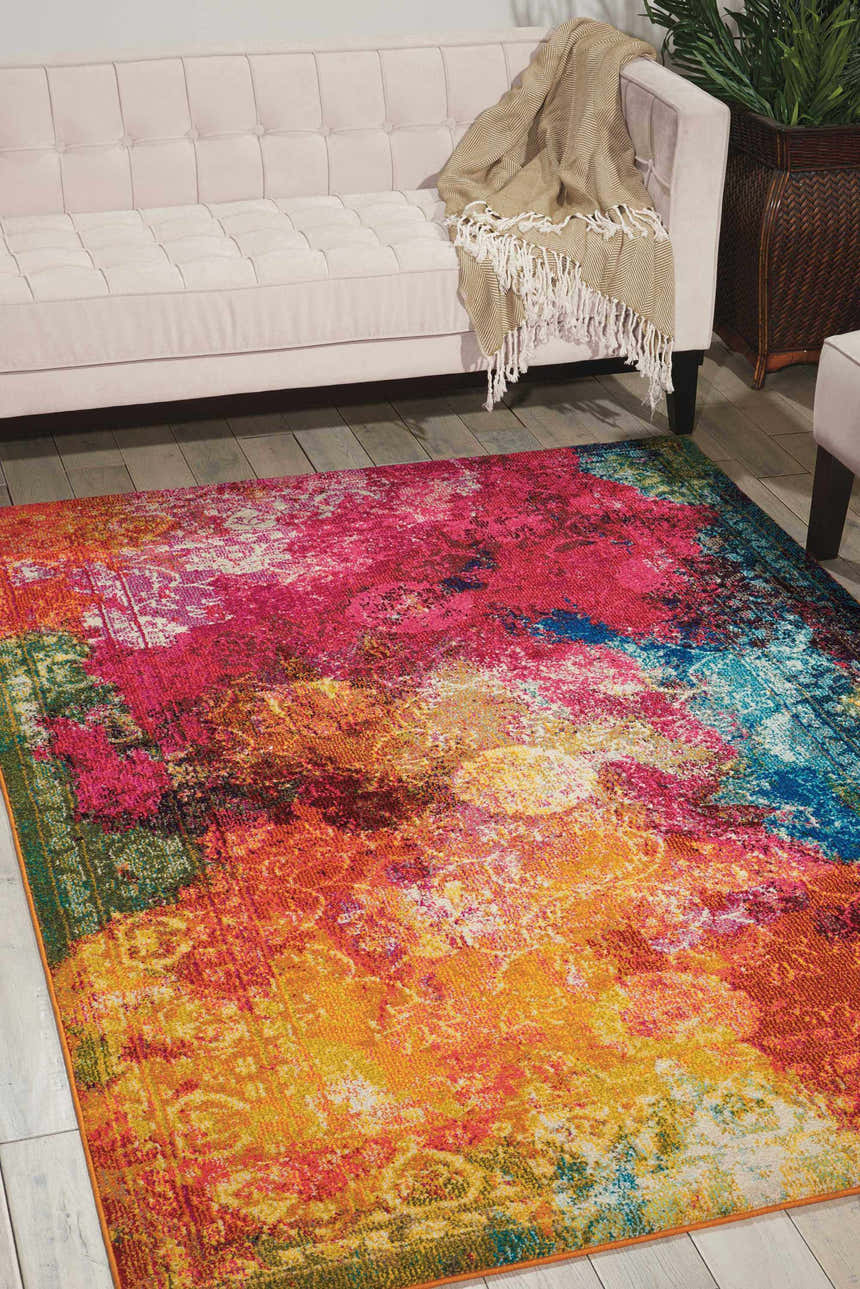 Living room scene with pink sofa and bright Nourison Celestial Seaglass rug in shades of pink, orange, yellow, and blue.