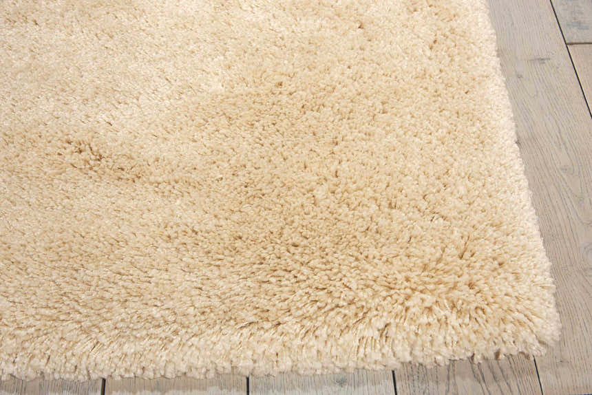 Close up of the plush texture of the Nourison Yummy Shag Bone Area Rug on light wood flooring.