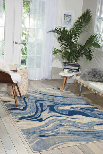 Light blue living room with a Nourison Somerset rug. Modern space with white furniture and a blue swirl pattern rug.