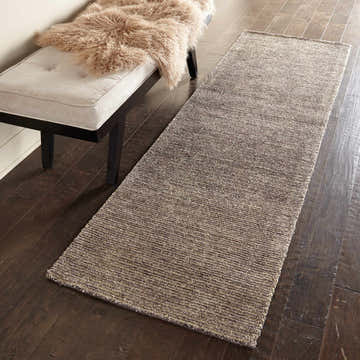 Hallway scene with a Nourison Weston Charcoal runner rug, taupe bench, and dark wood floors.