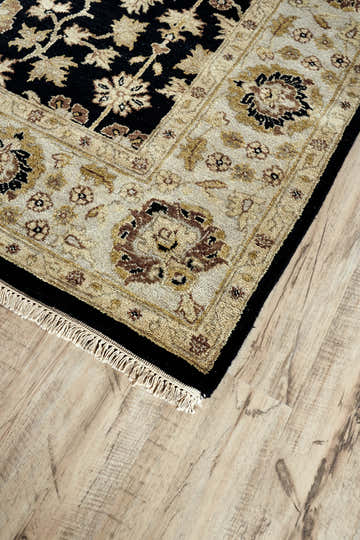 Close-up of Feizy Drake rug. Black and gold traditional oriental design with floral pattern and fringe detail. Wool texture. Corner