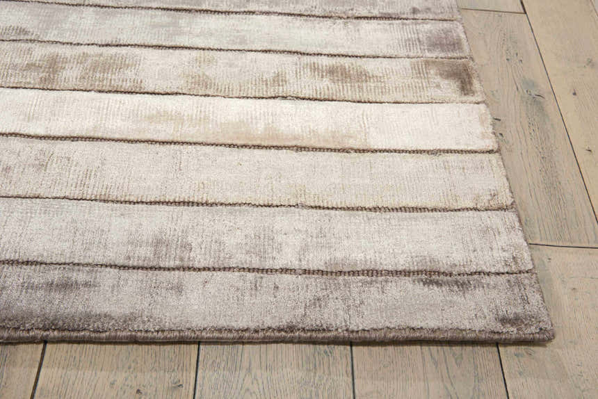 Close up of the textured Nourison Aura Silver Shadow rug with horizontal stripes on light wood floor.